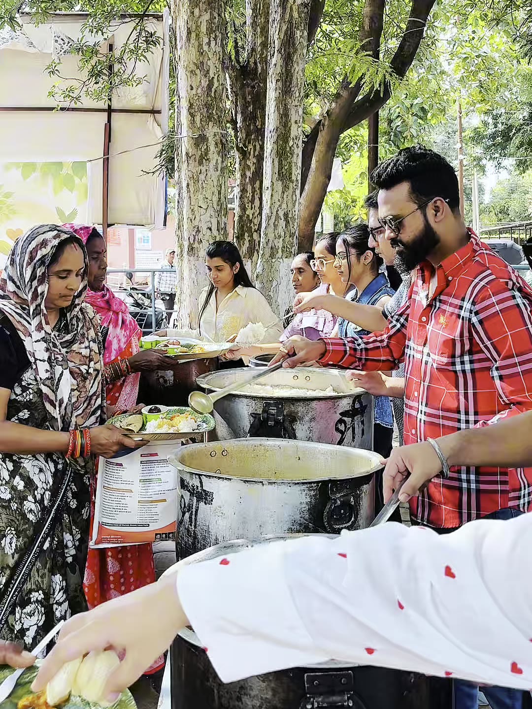 People receiving plates of freshly served food from Sarv Jeev Seva volunteers at the District Hospital, Dhamtari