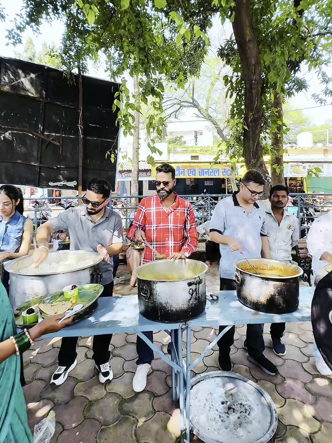 Sarv Jeev Seva volunteers serving hot food from large pots outside the District Hospital in Dhamtari